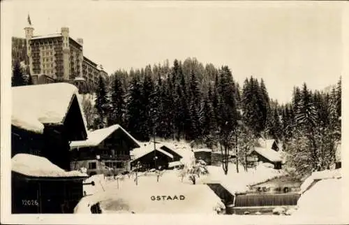 Ak Gstaad Saanen Kanton Bern, Schneelandschaft, Bauten, Wald, Gstaad Schriftzug, Winteridylle