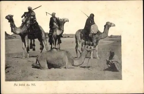 Ak Assouan Assuan Ägypten, Männer in traditioneller Kleidung reiten auf Kamelen in der Wüste.