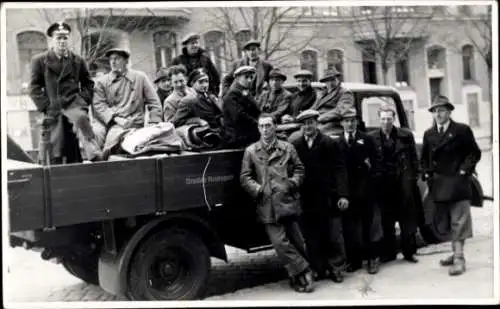 Ak Wien 10, Gruppe von Männern auf Lkw, winterliche Kleidung, Stadtansicht im Hintergrund