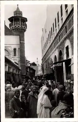 Ak Tunis Tunesien, Vielzahl von Menschen, eine enge Straße, Moscheeturm sichtbar, Souk-Szene