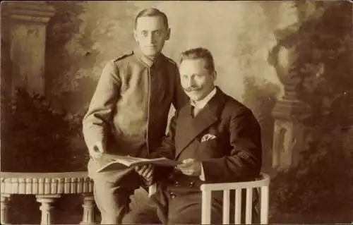 Ak Berlin Charlottenburg, Zwei Männer in Uniform und Anzug, die auf einem Stuhl sitzen und in ...