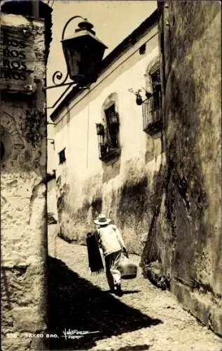 Ak Taxco Mexiko, Mann mit Hut, Tragetasche, enge Gasse,  Gebäude, Straßenlampe