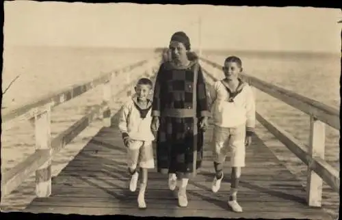 Foto Ak Frau mit zwei Jungen in Matrosenanzügen auf einer Seebrücke
