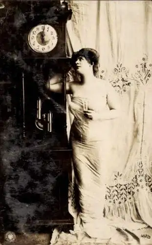 Ak Frau in engem schulterfreiem Kleid mit Sektglas, Standuhr
