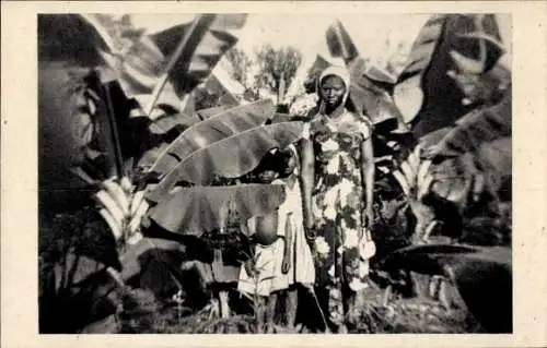 Ak Yoko Kamerun, Zwei Frauen zwischen Bananenstauden, traditionelle Kleidung, Schwarzweißaufnahme