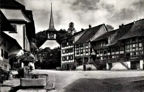 Ak Laupen Kanton Bern, Stadtszene mit Kirche, Fachwerkhäusern, Pflasterstraße, blühenden Geranien