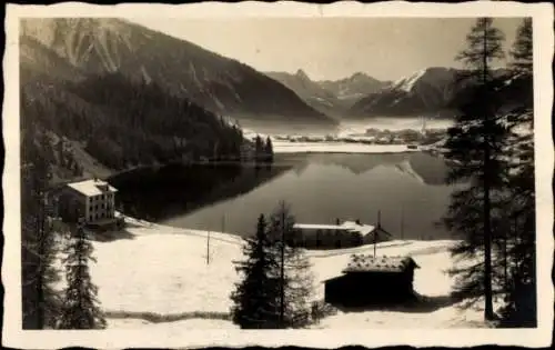 Ak Davos Kanton Graubünden, Blick auf den Davoser See, verschneite Berge, Gebäude im Vordergrund
