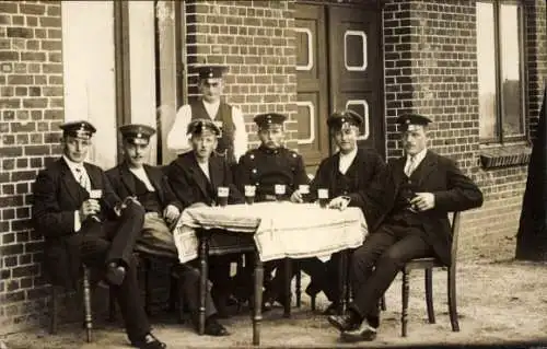 Foto Ak Männer mit Uniformmützen, Gruppenbild am Tisch, Biergläser