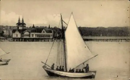 Ak Świnoujście Swinemünde Pommern, Segelboot auf dem Wasser, Gebäude im Hintergrund, ruhige Szene