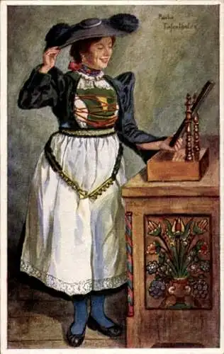 Ak Bozen Bolzano Südtirol, Eine junge Frau in Tracht steht vor einem geschnitzten Schrank.