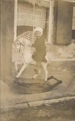 Foto Ak Kind auf einem Schaukelpferd, Portrait