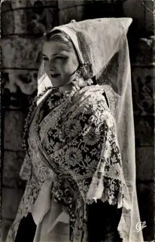 Ak Île de Ré Charente Maritime, Eine junge Frau in traditioneller Tracht steht vor einer Mauer.