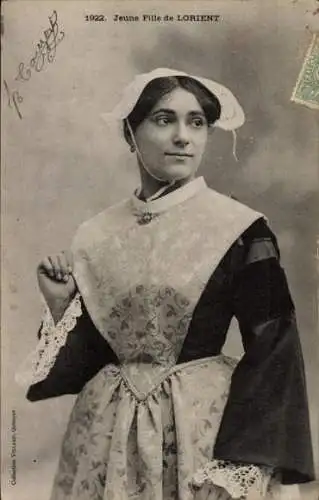 Ak Lorient Morbihan, Eine junge Frau in traditioneller Tracht steht vor einem Hintergrund mit ...