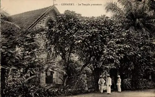 Ak Conakry Guinea, La Temple protestant, drei Personen, tropische Vegetation