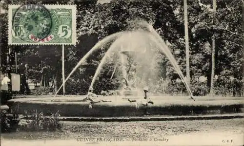 Ak Conakry Guinea, Brunnen mit Sprühwasser, Bäume im Hintergrund, Postwertzeichen