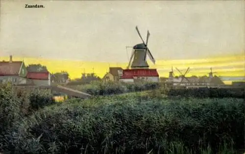Ak Zaandam Zaanstad Nordholland, Mühle, Häuser, Wiese, Sonnenuntergang, Wasser, beruhigende La...