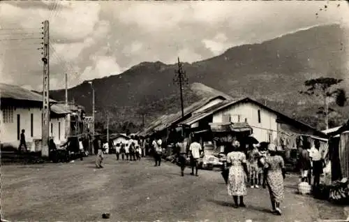 Ak Nkongsamba Kamerun, Straße mit Menschen, Häusern und Bergen im Hintergrund, Marktszene