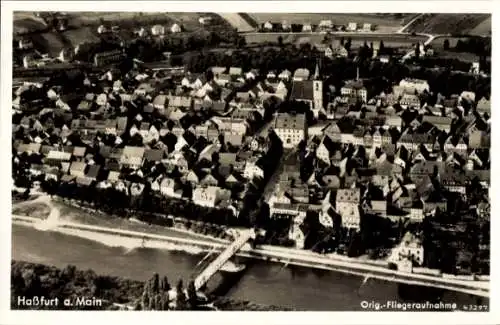 Ak Haßfurt am Main Unterfranken, Luftaufnahme von Haßfurt, Fluss, Brücke, Häuser, Landschaft