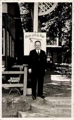 Foto Ak Berlin Neukölln, Mann in schwarzem Anzug, Restaurant, Tische