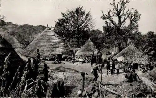 Ak Conakry Guinea, Dorfansicht, traditionelle Hütten, Menschen in Tracht, ländliche Szene