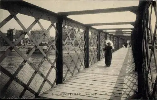 Ak Alfortville Val de Marne, Brücke, Spaziergängerin mit Schirm, Gebäude im Hintergrund, Wasser