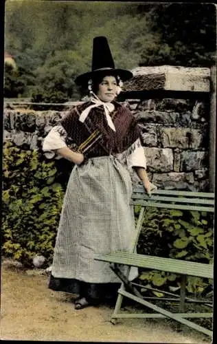 Ak Swansea Wales, Eine junge Frau in traditioneller walisischer Tracht steht vor einer Steinma...