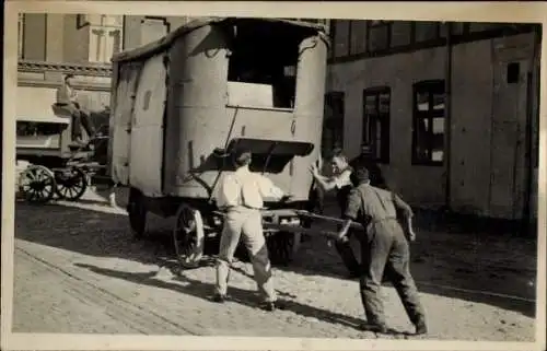 Foto Ak Männer schieben ein Fahrzeug, Kutsche, Pkw-Anhänger