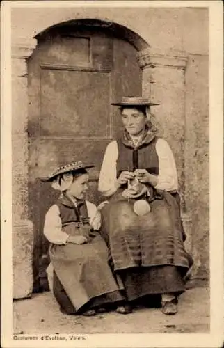 Ak Evolène Kanton Wallis, Zwei Frauen in Tracht sitzen vor einer Tür.