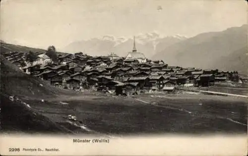 Ak Münster Kanton Wallis, Historisches Dorf, viele Holzhäuser, Berglandschaft, Kirche im Hinte...