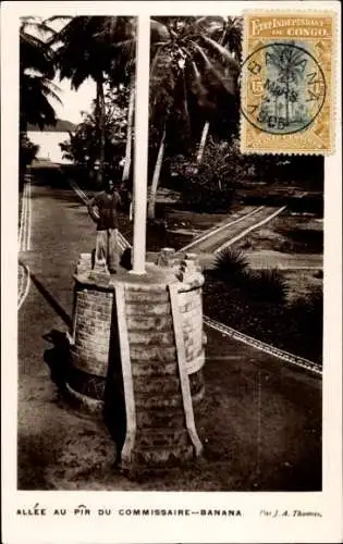 Ak Banana DR Kongo Zaire, Statue, Flaggenmast, Pflanzen,  Kulisse, J. A. Thomas