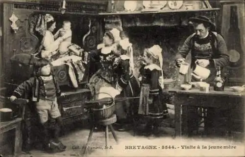 Ak Bretagne, bretonische Tracht, Eine junge Frau sitzt auf einem Stuhl und hält ein Baby im Ar...