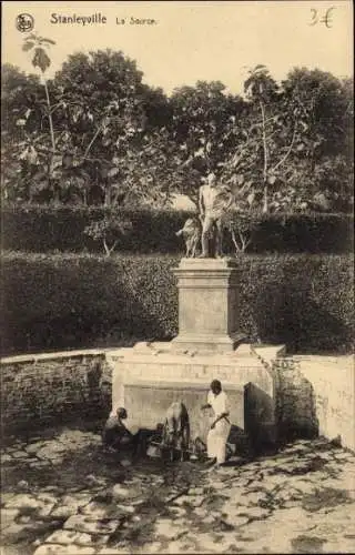 Ak Kisangani Stanleyville DR Kongo Zaire, Brunnen mit Statue, zwei Personen im Wasser, Bäume im H