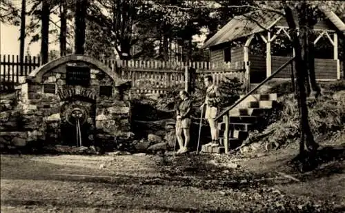 Ak Fehrenbach Masserberg in Thüringen, Brunnen mit Steinstufen, zwei Personen in der Nähe, Holzhä