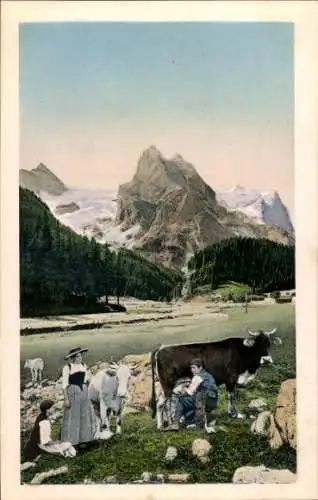 Ak Menschen in Volkstrachten, Junge melkt eine Kuh, Berge