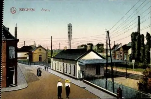 Ak Izegem Iseghem Westflandern, Bahnhofgebäude, Schienen, Straßenansicht, zwei Personen