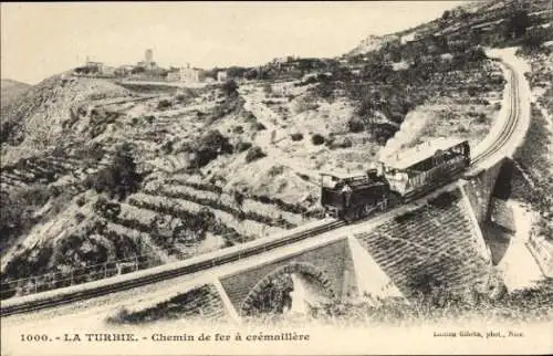 Ak La Turbie Alpes Maritimes, Eisenbahn auf einer Brücke, hügelige Landschaft, Gebäude im Hinterg