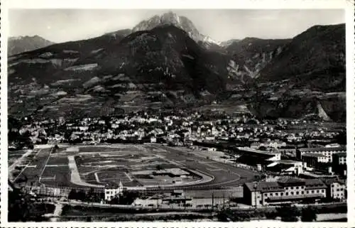 Ak Meran Merano Südtirol, Sicht auf eine Stadt mit einem Rennplatz, Berge im Hintergrund