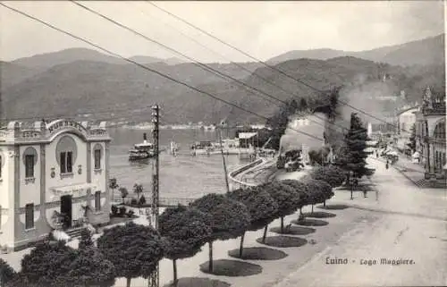 Ak Luino Lago Maggiore Lombardia, Lago Maggiore, Hafenansicht, elegantes Gebäude, Berge im Hinter