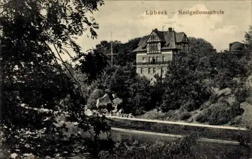 Ak Hansestadt Lübeck,  Navigationsschule, Gebäude am Flussufer, Bäume im Vordergrund
