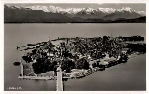 Ak Lindau am Bodensee Schwaben, Luftaufnahme von Lindau, Berge im Hintergrund, Wasser,  Stadtansi