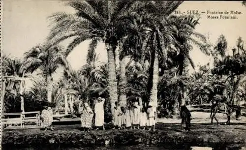 Ak Suez Ägypten, Moses Fountain, Palmen, Menschen in traditioneller Kleidung, Wüstenlandschaft