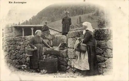 Ak Auvergne, am Dorfbrunnen, Frauen und Kinder in Tracht