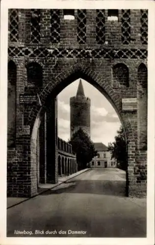Ak Damm Jüterbog in Brandenburg, Blick durch das Dammtor, Ziegelsteinarchitektur, Turm im Hint...