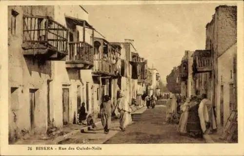 Ak Biskra Algerien, Straße mit traditionellen Häusern, Menschen in traditionellen Kleidern