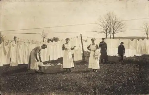 Foto Ak Frauen hängen Wäsche auf, Bettwäsche