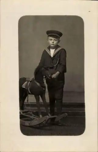 Foto Ak Junge in Matrosenuniform, Schaukelpferd
