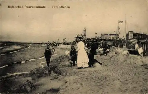 Ak Ostseebad Warnemünde Rostock, Strand mit Menschen, Kinder am Wasser, Hütten, Flaggen, Gebäude 