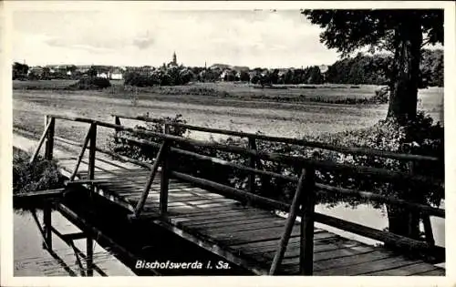 Ak Bischofswerda in Sachsen, Brücke über Wasser, Landschaft, Stadtansicht im Hintergrund, Wolken