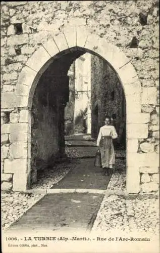 Ak La Turbie Alpes Maritimes, Frau mit Eimer, Steingasse, Torbogen, Landschaft,  Architektur