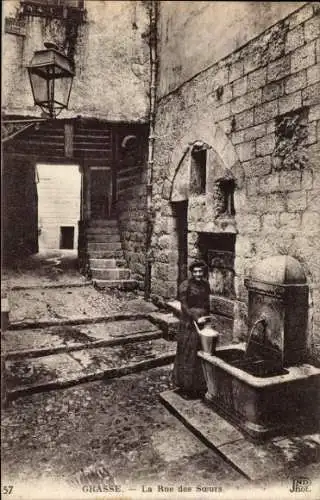 Ak Grasse Alpes Maritimes, Wasserquelle, Frau mit Eimer, enge Gasse,  Architektur